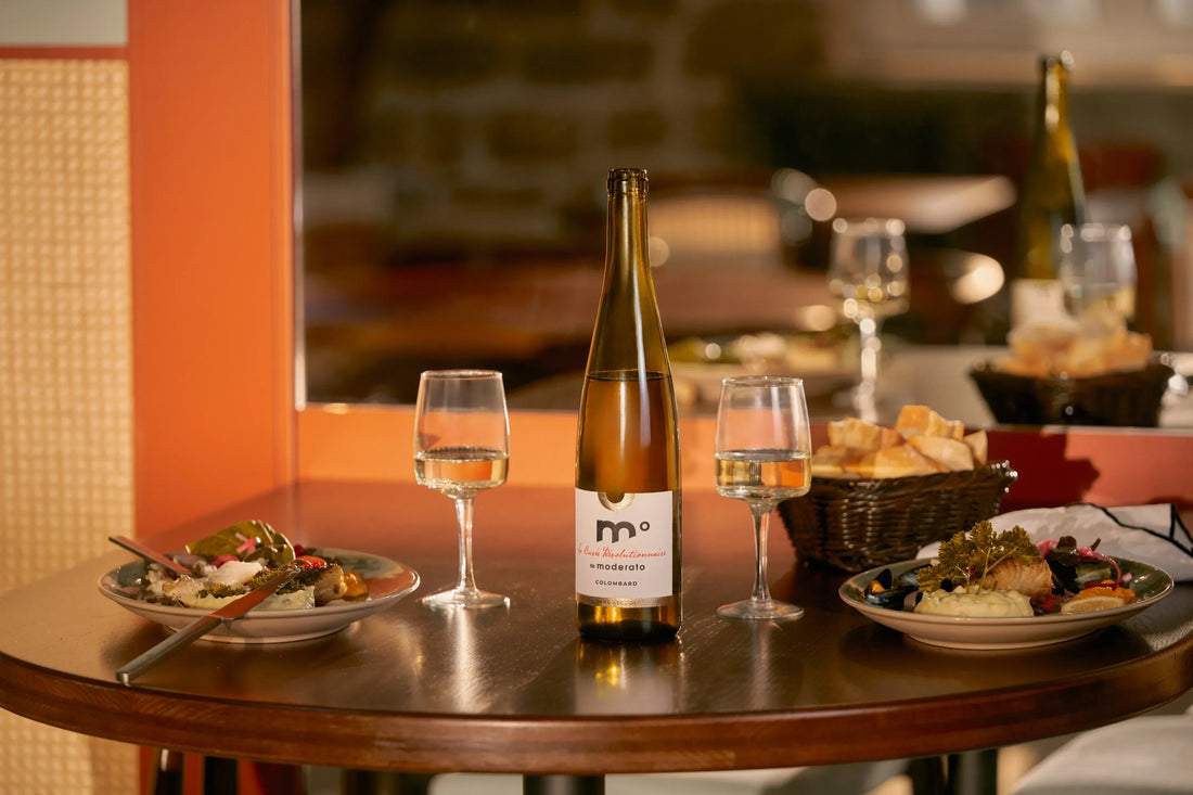 Sober Table alcohol-free white wine served at dinner table with food pairing and glasses in a warm restaurant setting.