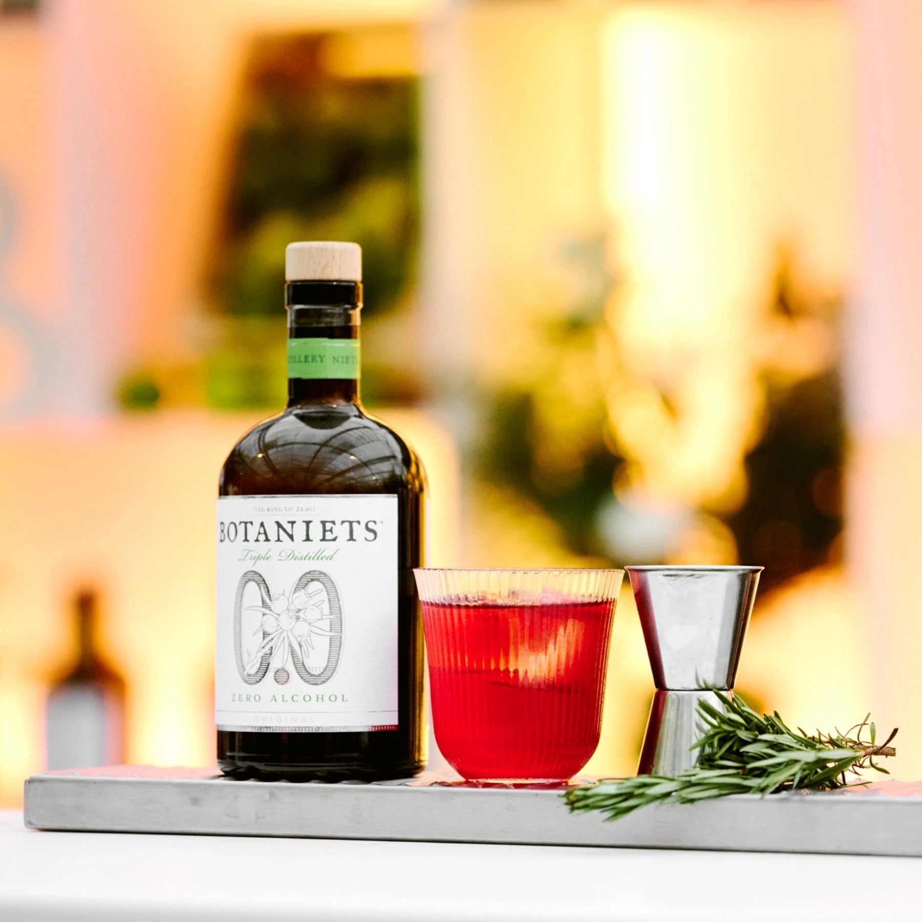 Botaniets Original alcohol-free botanical spirit used in a red cocktail served in a glass with bar tools.