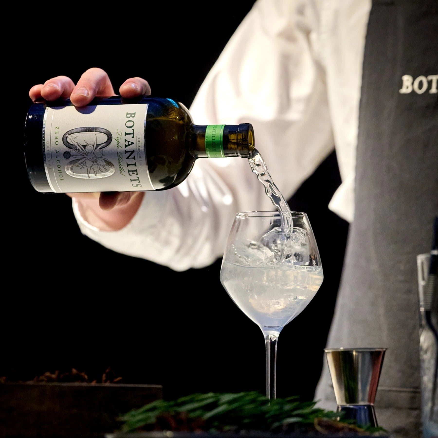 Botaniets Original alcohol-free botanical spirit being poured into a glass with ice for a cocktail serve.