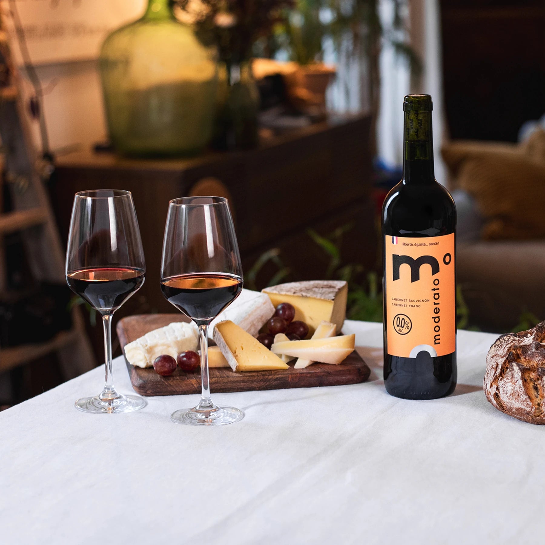 Moderato alcohol-free red wine served with cheese and grapes on a table, relaxed dining setting.