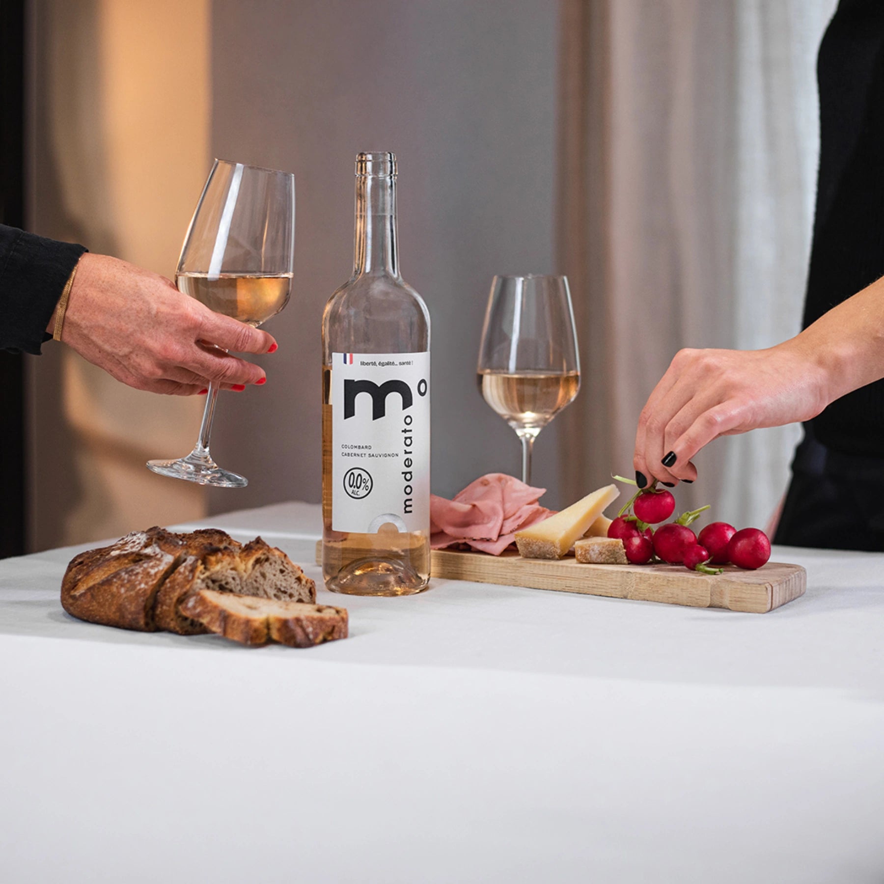 Moderato alcohol-free rosé wine served with bread, cheese and fresh ingredients, casual dining moment.