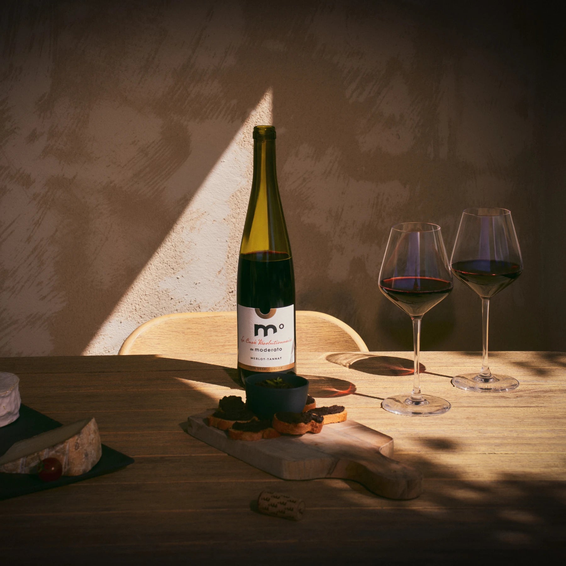 Moderato Merlot-Tannat alcohol-free red wine served on a table with glasses and appetizers, warm dining setting.