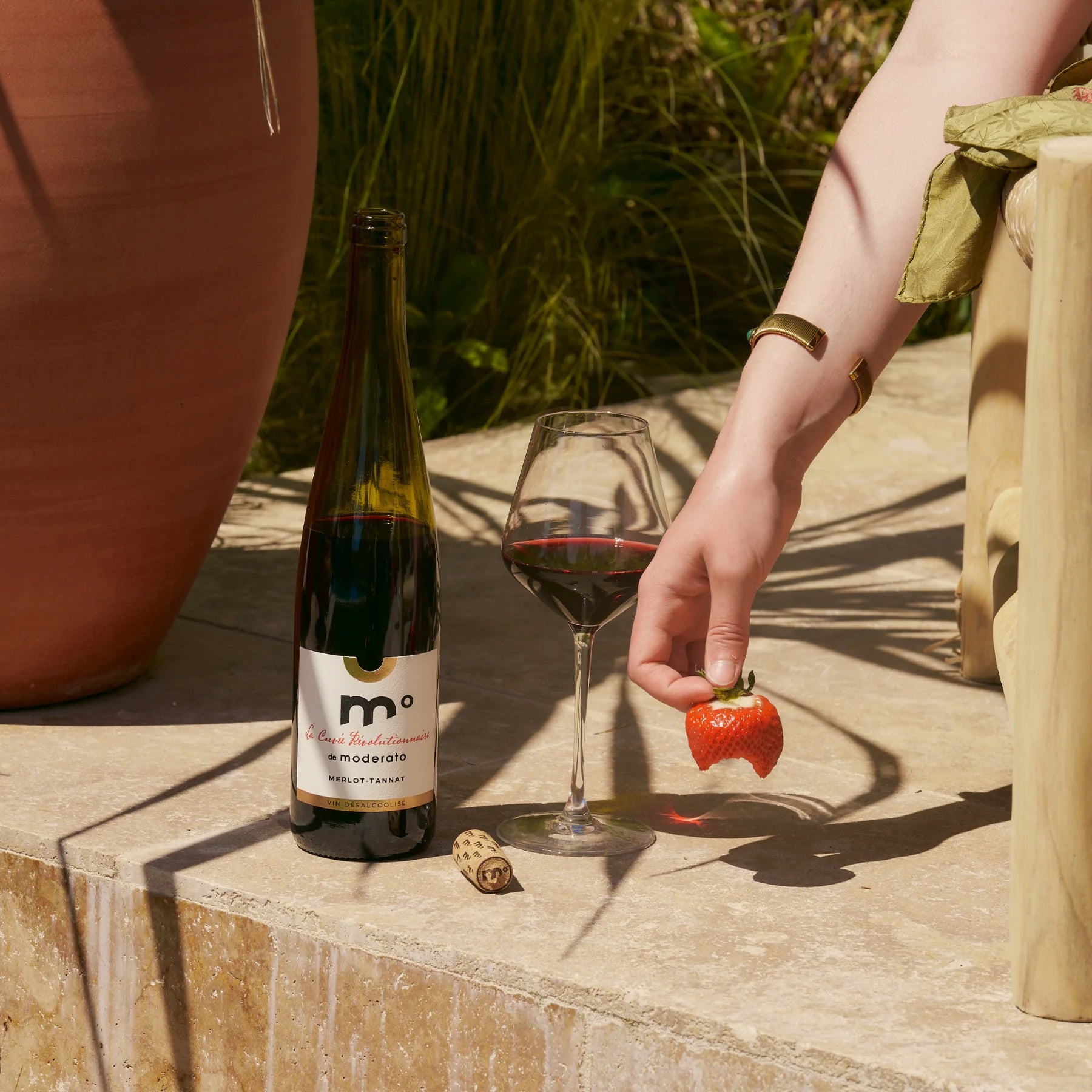 Moderato Merlot-Tannat alcohol-free red wine served outdoors with a glass and fresh strawberry, sunny terrace scene.