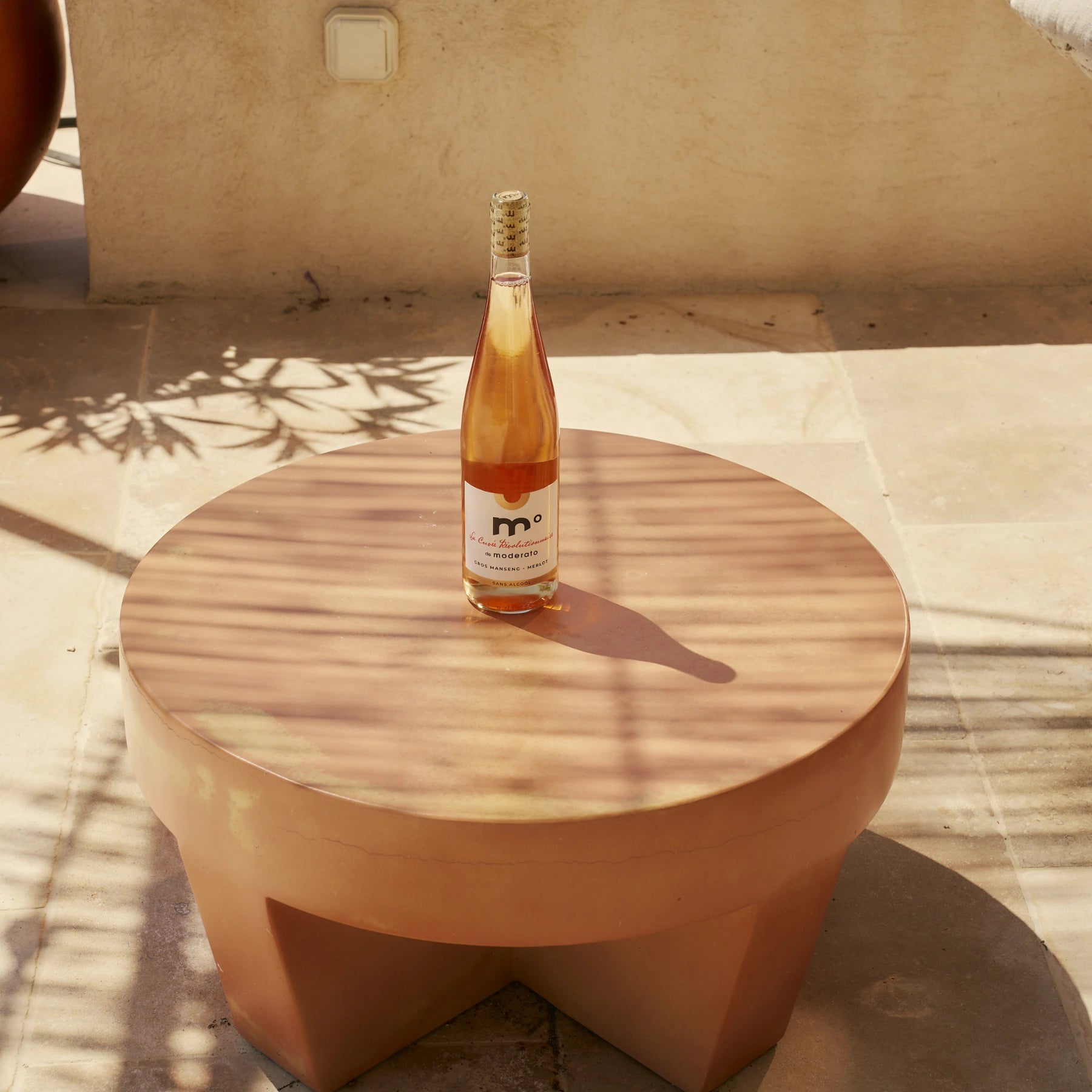 Moderato Cuvée Révolutionnaire rosé Gros Manseng Merlot alcohol-free wine on round outdoor table in sunlight