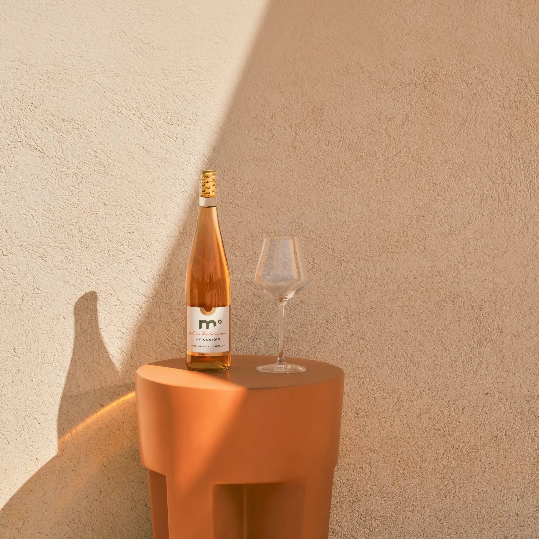 Moderato Cuvée Révolutionnaire rosé Gros Manseng Merlot alcohol-free wine bottle with empty glass on pedestal