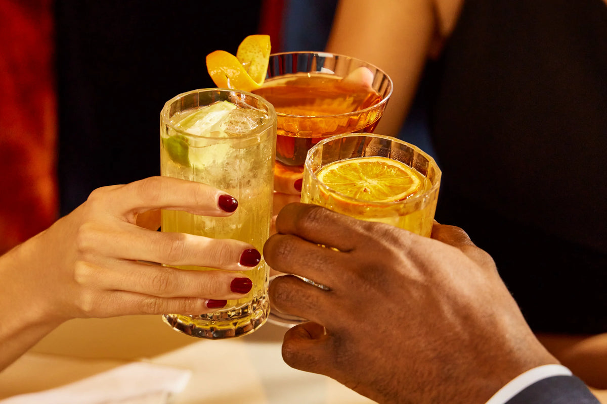 Sober Table alcohol-free spirits cocktails served in glasses with citrus garnish during a social toast.