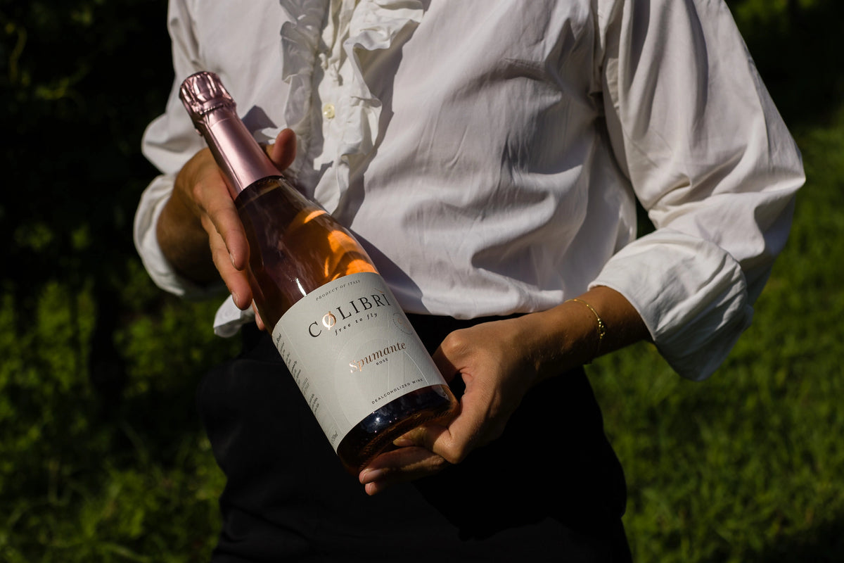 Italian Colibri Spumante Rosé alcohol-free sparkling wine 0.0% held in hand outdoors lifestyle scene.