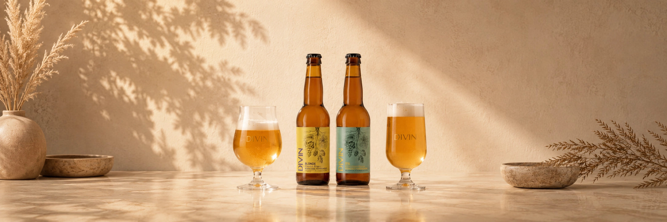 Divin Blonde and IPA alcohol-free beer bottles with golden beer glasses in a warm, sophisticated panoramic setting.