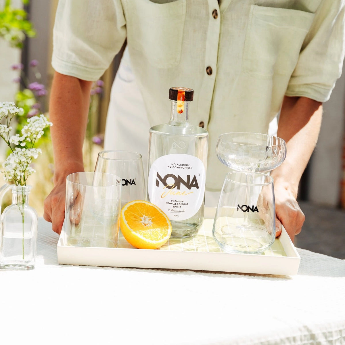 NONA June 0.0% alcohol-free spirit bottle with glassware and fresh orange on a serving tray.