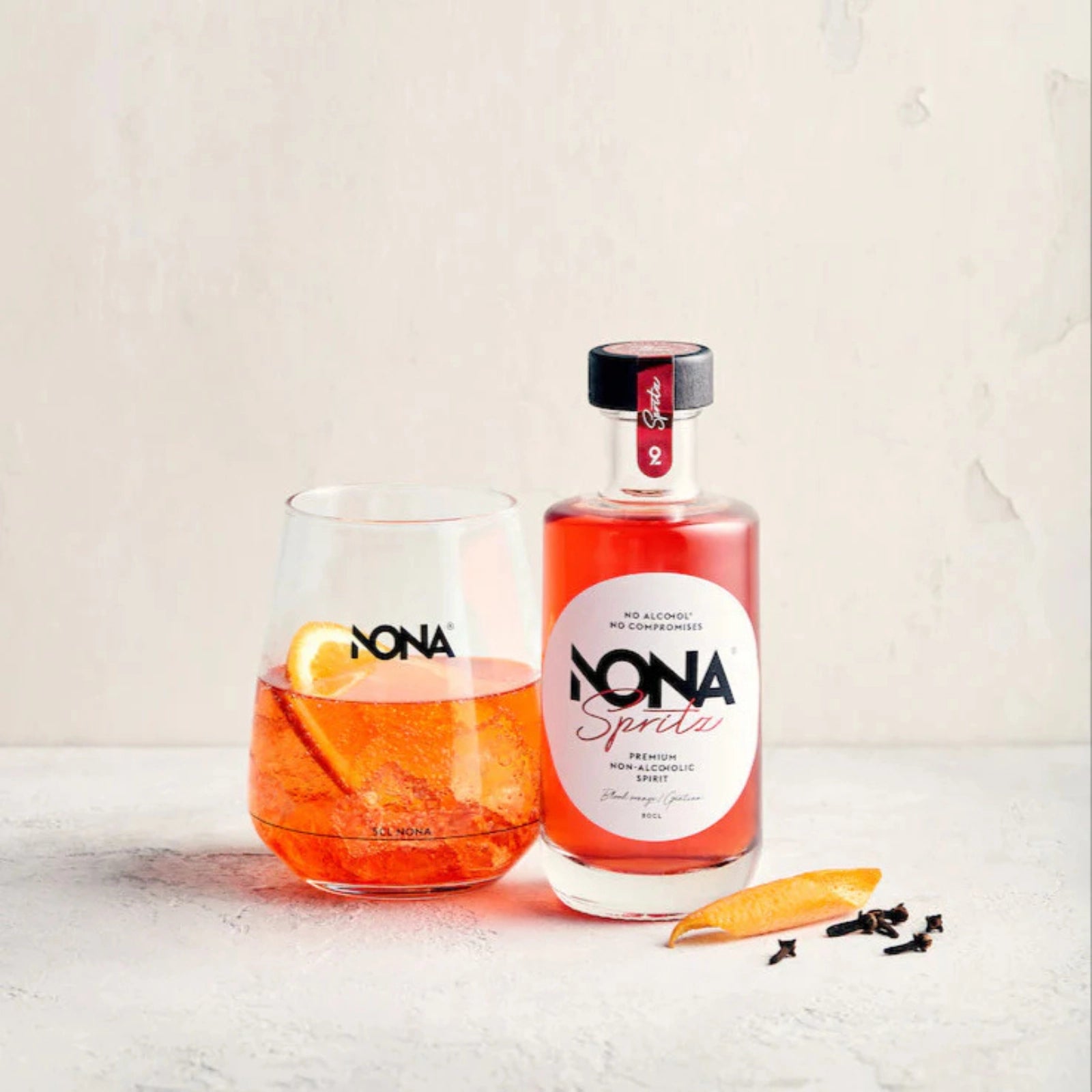 200 ml Bottle of NONA Spritz and glass of NONA Spritz and Tonic mocktail on a light background