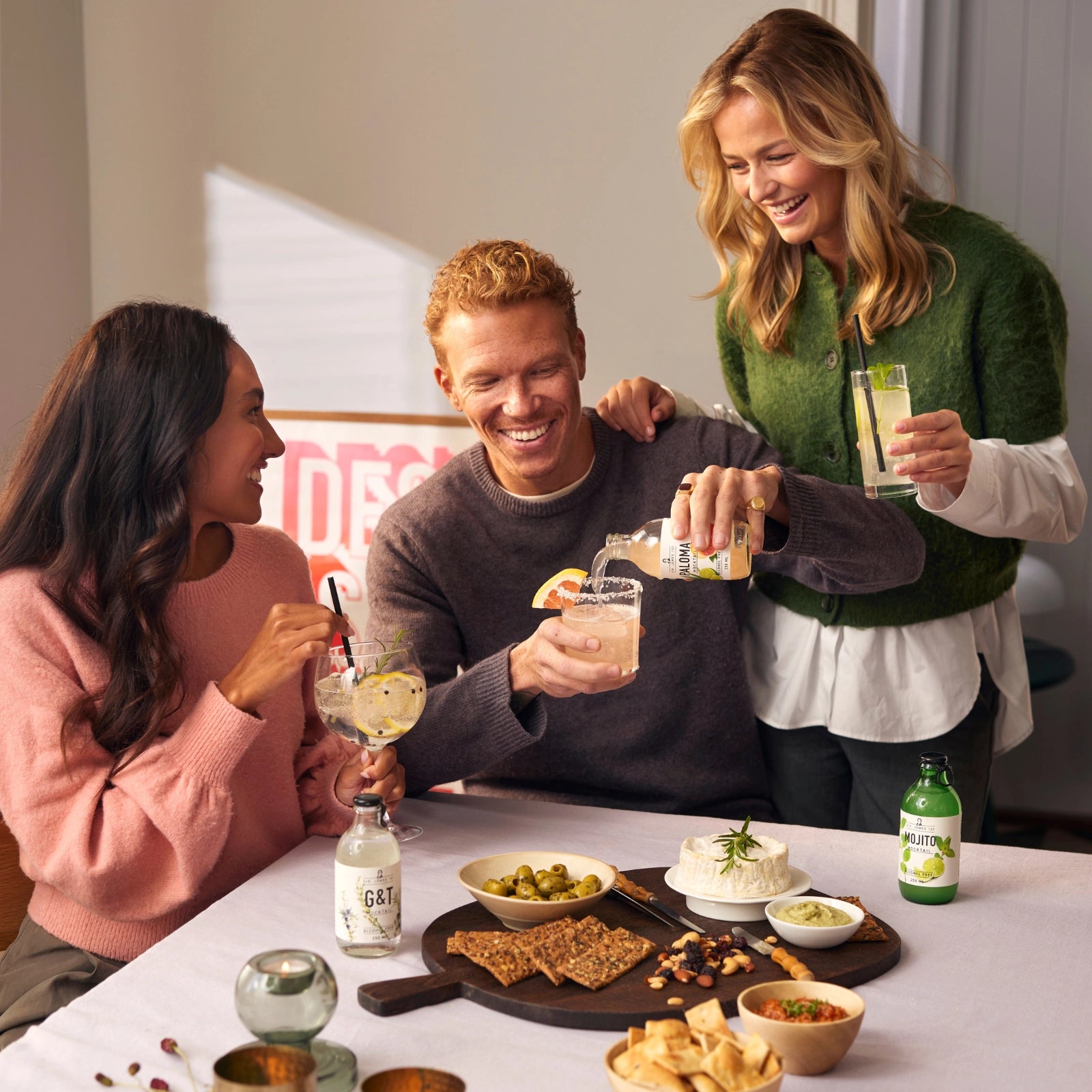 Friends enjoying Sir James 101 alcohol-free mocktails together at a table with snacks and drinks