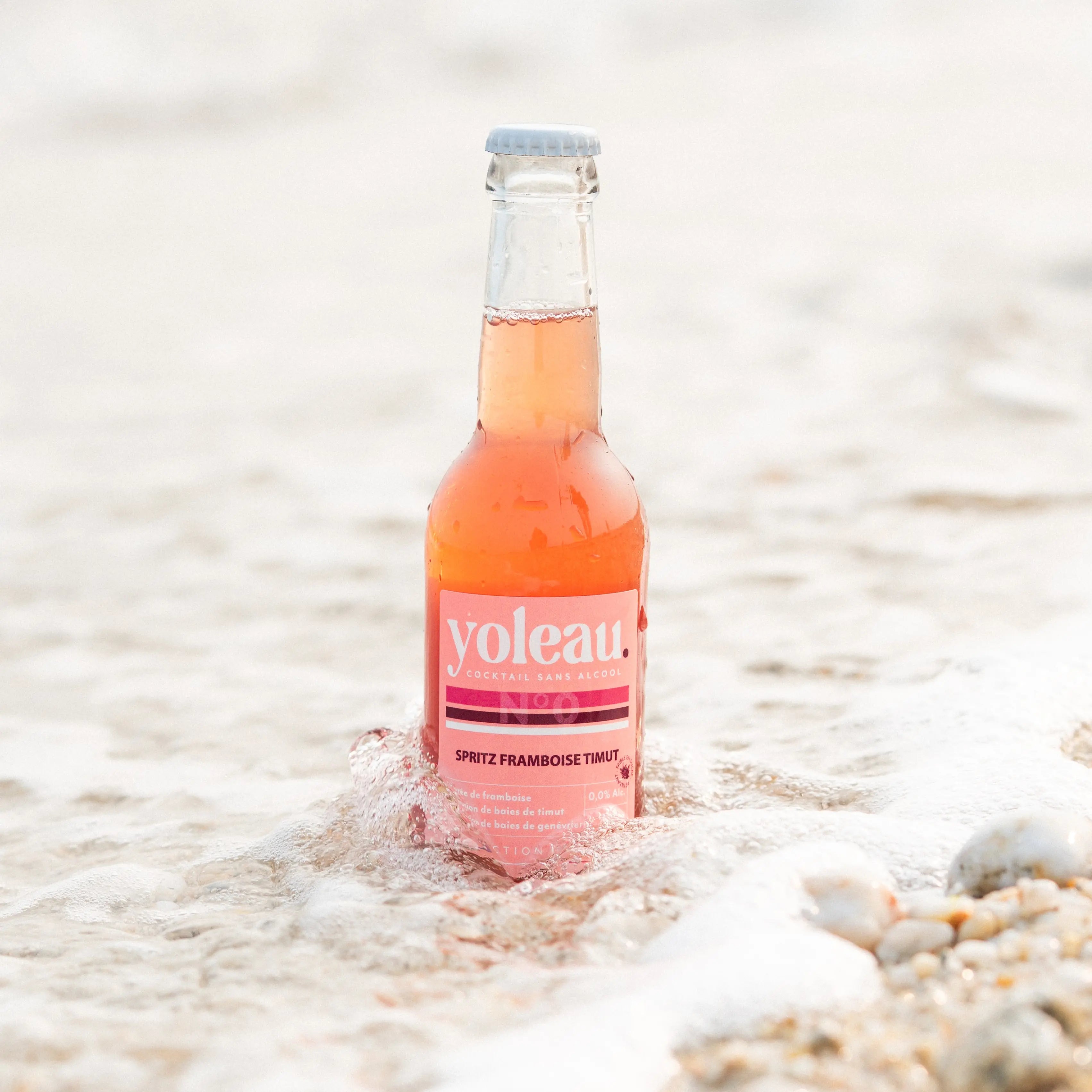 Yoleau Raspberry Spritz mocktail 0.0% alcohol-free drink bottle 250 ml standing in sea water.