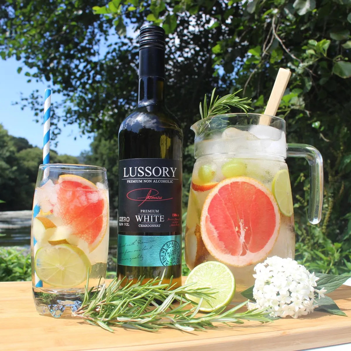 LUSSORY Premium Chardonnay Non-Alcoholic White Wine bottle with a refreshing white sangria, citrus fruits, and rosemary garnish served outdoors.